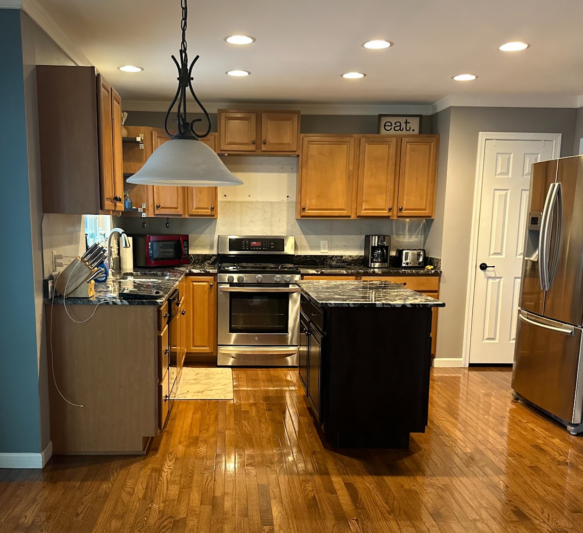 A kitchen with wood cabinets and granite counters, before a cabinet repaint
